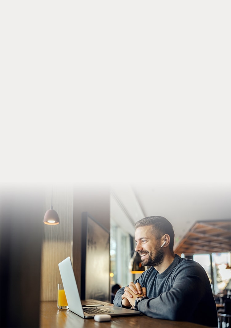 Homem sorrindo enquanto olha para o notebook.