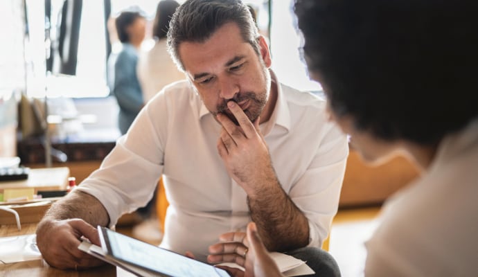 Homem olhando para outro homem que está usando um laptop