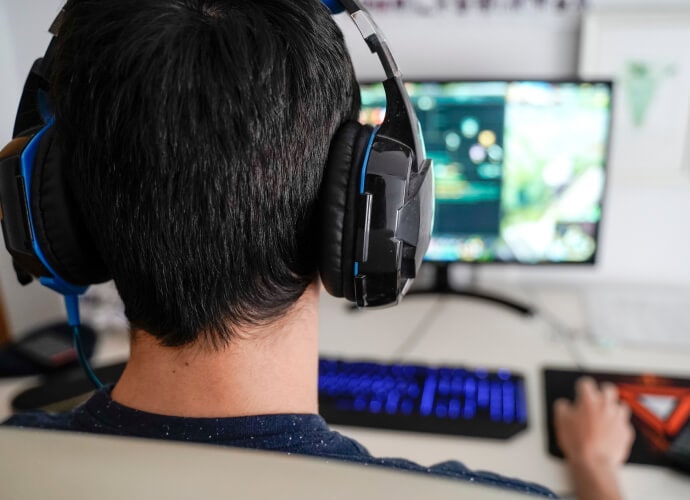 Homem usando fones de ouvido sentado em frente a um computador