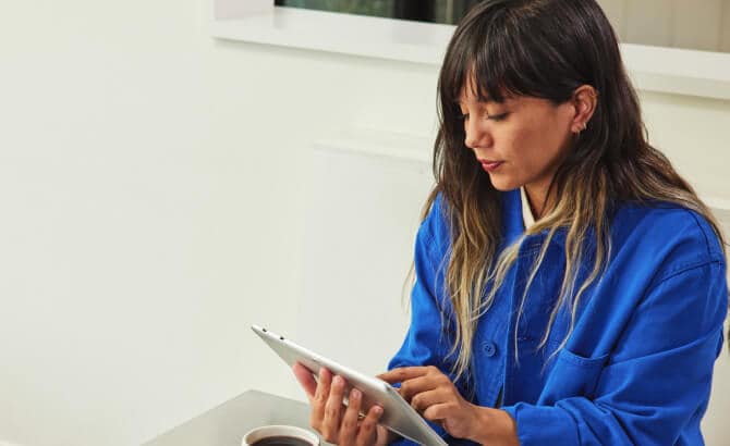 Mulher diante de um tablet sobre uma mesa