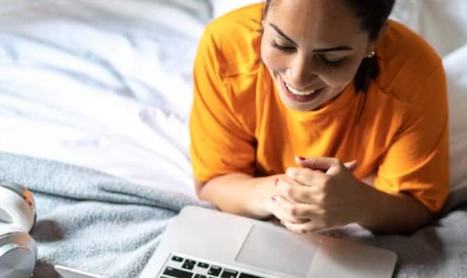 Mulher sorrindo ao olhar para o laptop