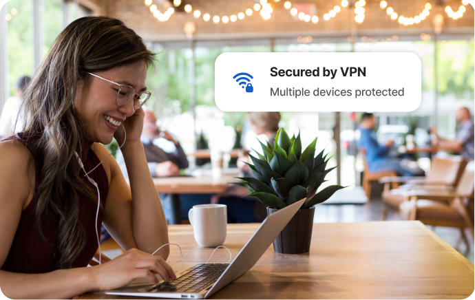 Mulher em um café rindo diante da tela de um laptop