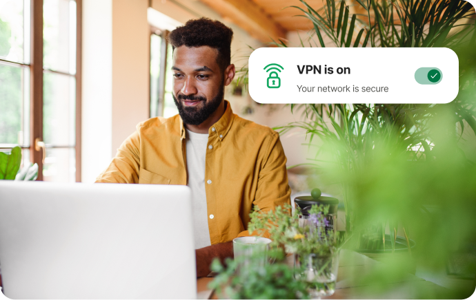 Homem cercado por plantas sorrindo diante de um laptop